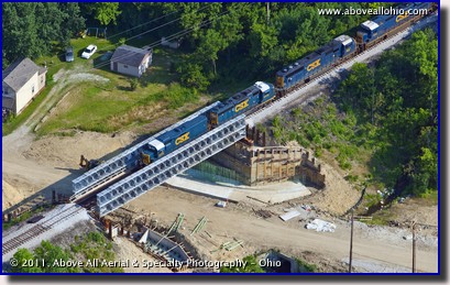 An aerial view of a freight train crossing a temporary steel bridge near Columbus, OH