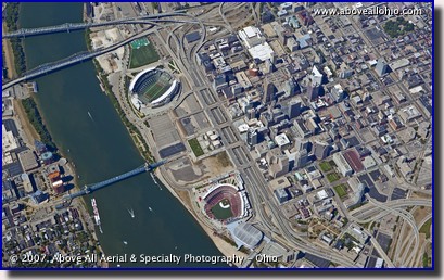 A very steep oblique aerial view of downtown Cincinnati, OH, showing the Ohio River, Paul Brown Stadium, and Great American Ballpark.